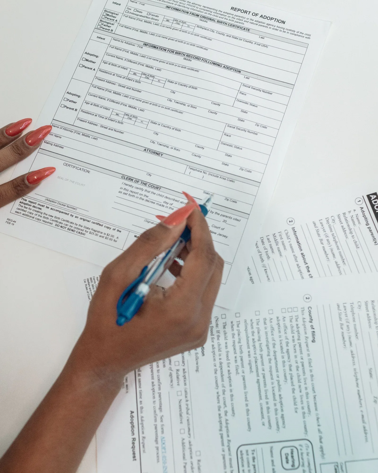 Une main remplit au stylo le formulaire de déclaration, posé sur un bureau en bois