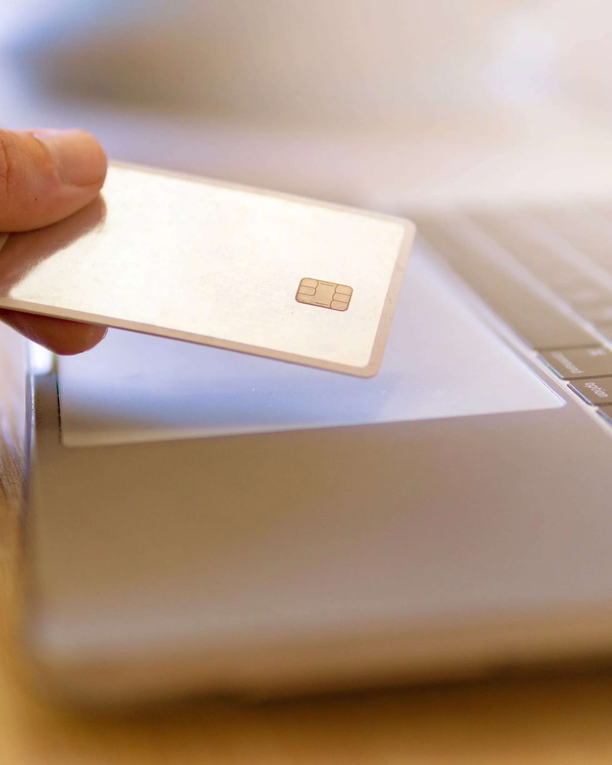 Une main tient sa carte bancaire devant l’ordinateur portable, au moment de préparer un virement